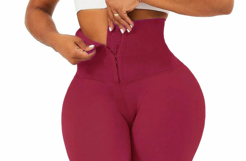 Woman wearing high-waisted maroon corset leggings and a white crop top