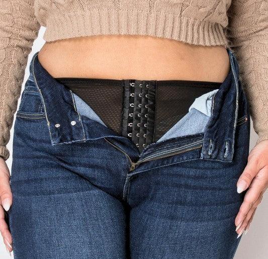 Woman wearing blue jeans with open fly, revealing a black waist trainer underneath